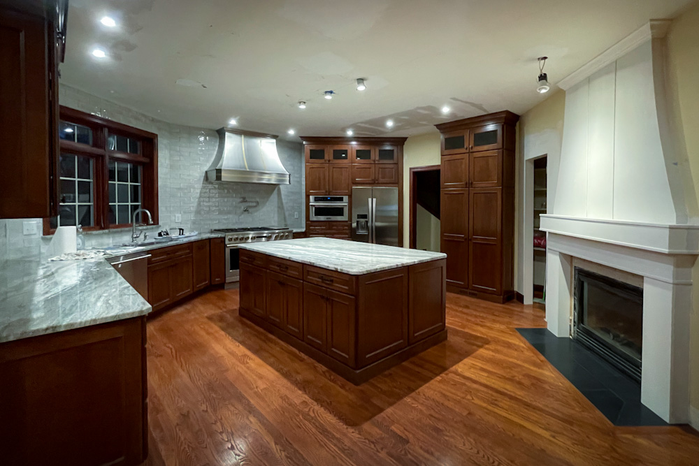 Stonewall Renovations cherry kitchen with an island, stainless steel hood, and fireplace