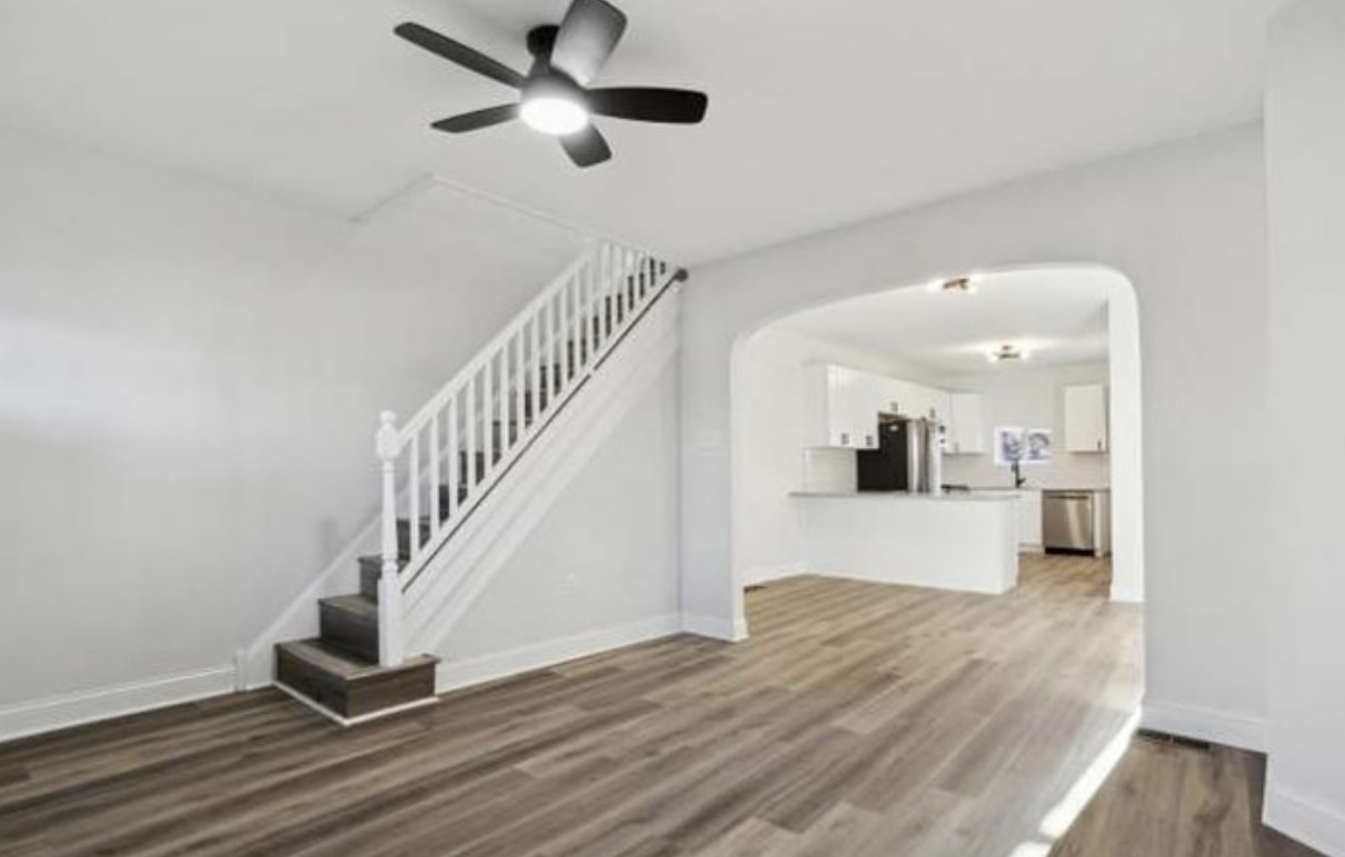 Stonewall Renovations open living room with renovated staircase and adjoining kitchen
