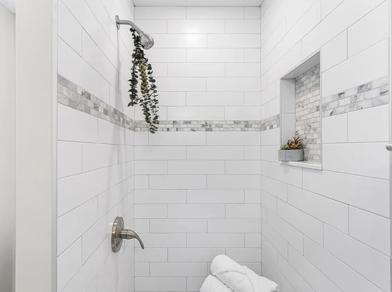 Stonewall Renovations white subway tile shower with accent band and recessed niche